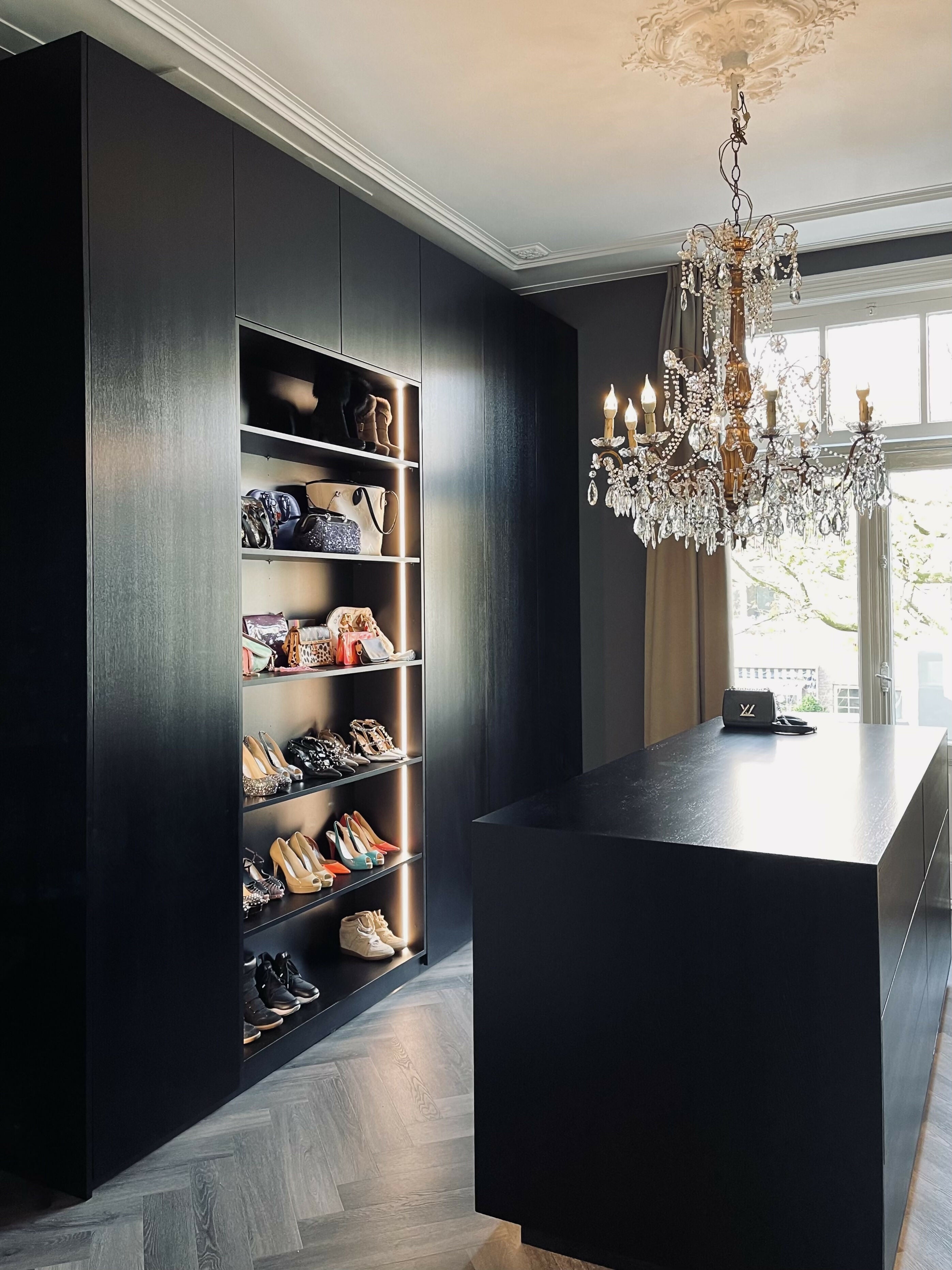 Luxe inloopkast met maatwerkkasten en chandelier-L4 Elvire-donkere houtfineer,dressing room,elegant design,garderobekast,high end interieur,ingebouwde verlichting,inloopkast,klassieke elementen,kroonluchter,luxe afwerking,maatwerkkasten,opbergruimte,slaapkamer kast,stijlvolle opberging,visgraatvloer,woonkamer-Luxe inloopkast met maatwerk & chandelier | STUDIO L4 Interieur-OBLY