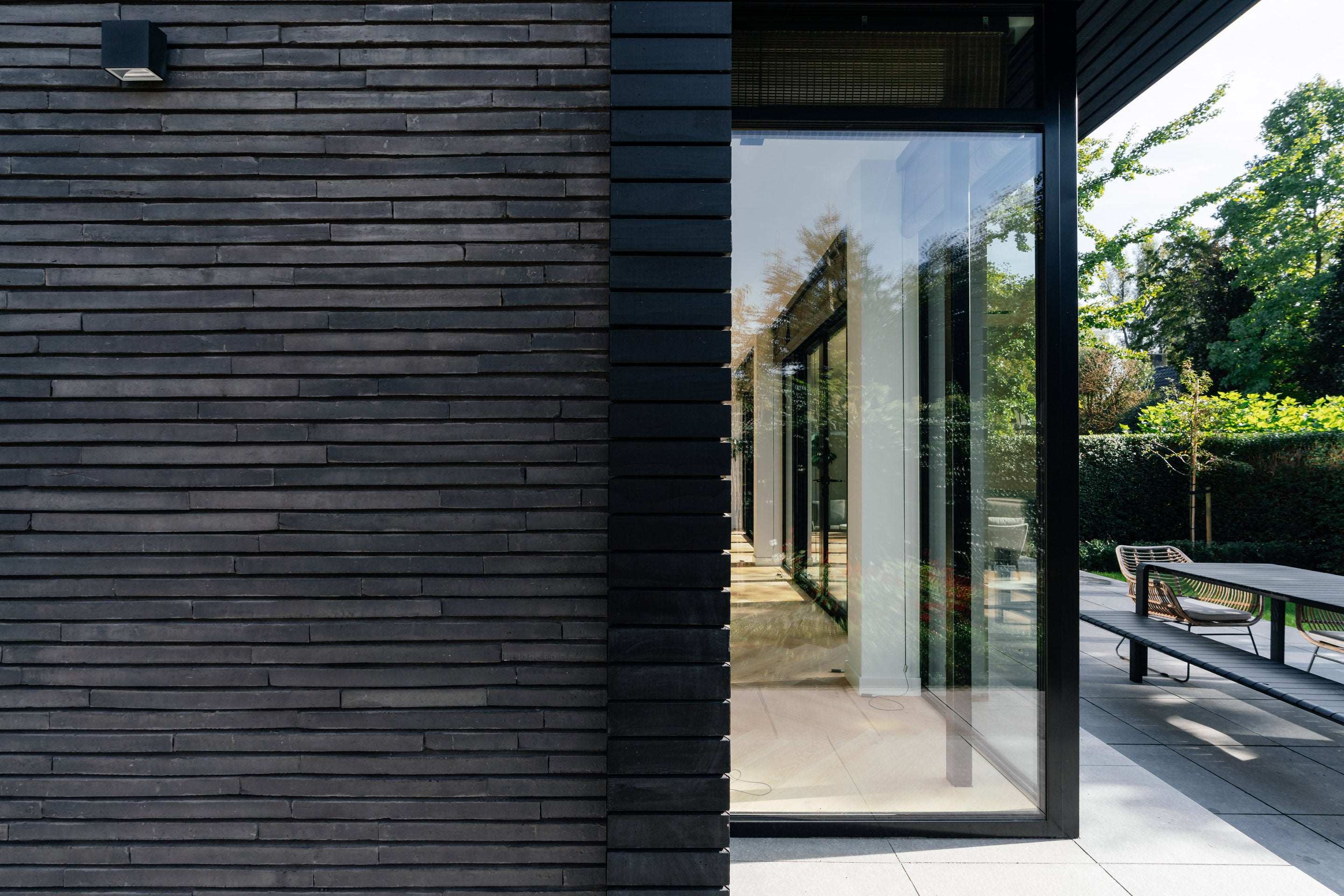 Moderne aanbouw met stalen kozijnen en grote glaspartijen als eigentijdse uitbreiding van een karakteristieke jaren '30 woning.