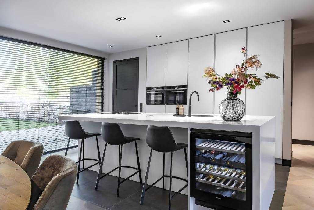 Kookeiland met wijnkast-Cora Techniek-Corian keukenwerkblad,designkeuken met wijnklimaatkast,Keuken,keuken met BORA inductiekookplaat,kookeiland met wijnkast,luxe leefkeuken inspiratie,moderne keuken met kookeiland,strakke maatwerk keuken,witte keuken met bar-Kookeiland met luxe wijnkast-OBLY