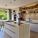Lichte maatwerk keuken met travertinlook kookeiland en open wandplanken