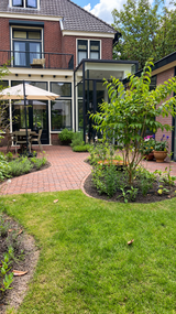 Groene stadstuin met gebogen klinkerpaden en glazen aanbouw-Pien de Bel-glazen aanbouw,groene tuin,klinkerpaden,stadstuin,Tuinontwerp-Groene stadstuin met klinkerpaden en glazen aanbouw-OBLY