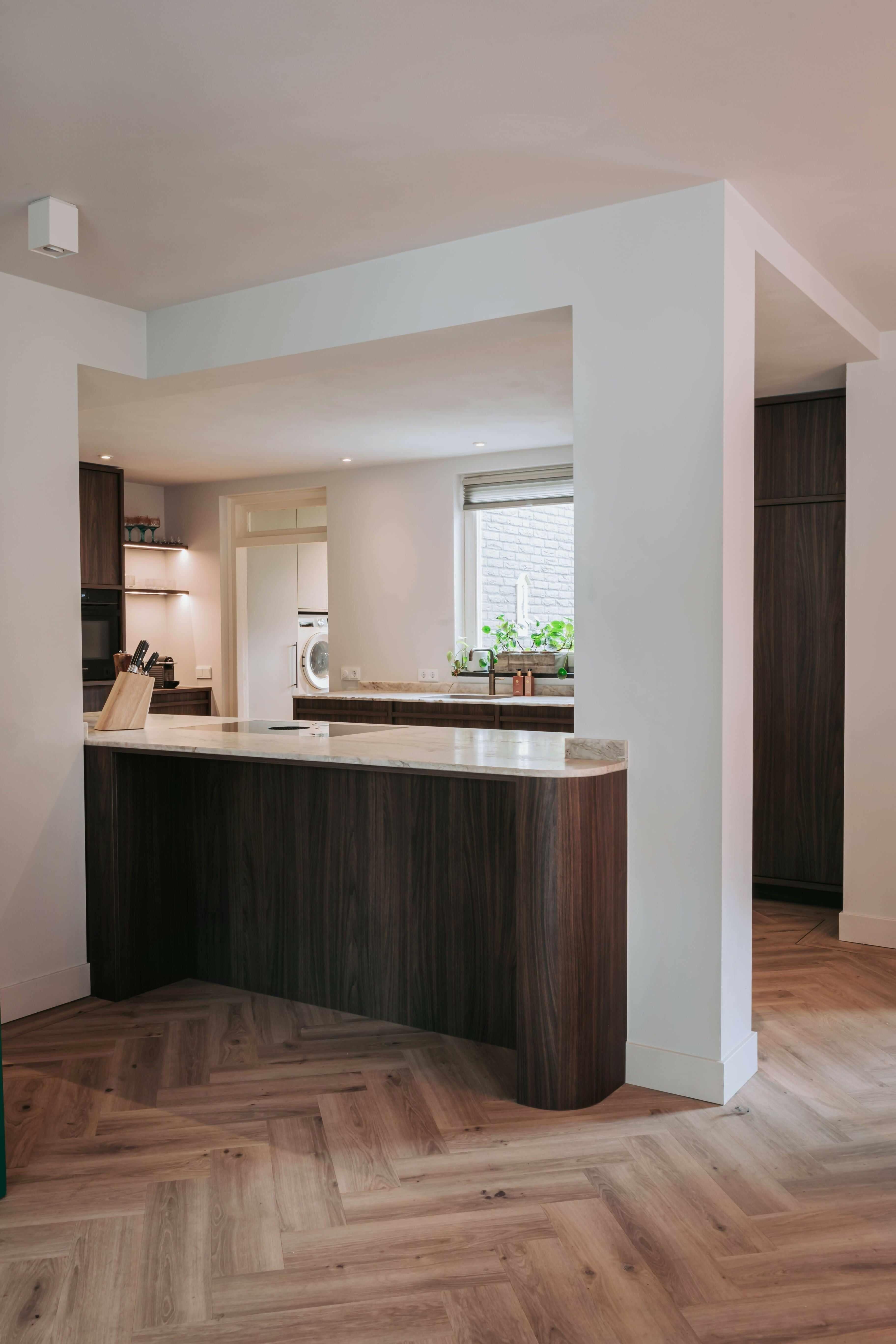 Japandi Keuken & Woonkamer Integratie-Hout en Vorm-design keuken interieur,Japandi,japandi keuken,Keuken,keuken met donker hout,keuken met natuursteen blad,luxe maatwerk keuken,minimalistische keuken,moderne japandi stijl,Woonkamer-OBLY