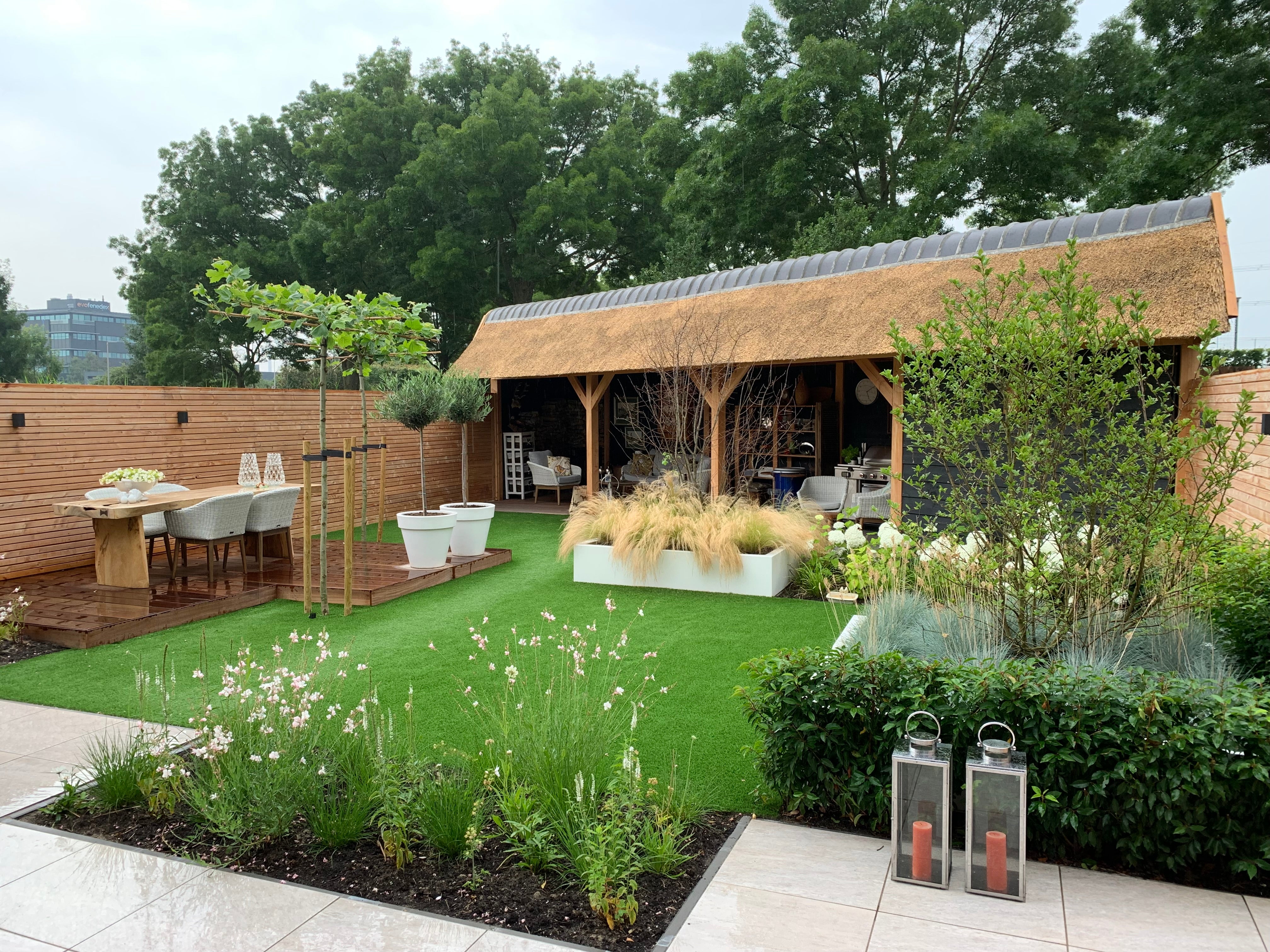 Sfeervolle villatuin met rietgedekt buitenverblijf-Leonardus buiten-exclusieve tuinontwerp,hardhouten vlonder,landelijke moderne tuin,luxe buitenleven,luxe tuin inspiratie,rietgedekt buitenverblijf,sfeervolle villatuin,tuin,villatuin-Luxe villatuin met rietgedekt buitenverblijf-OBLY