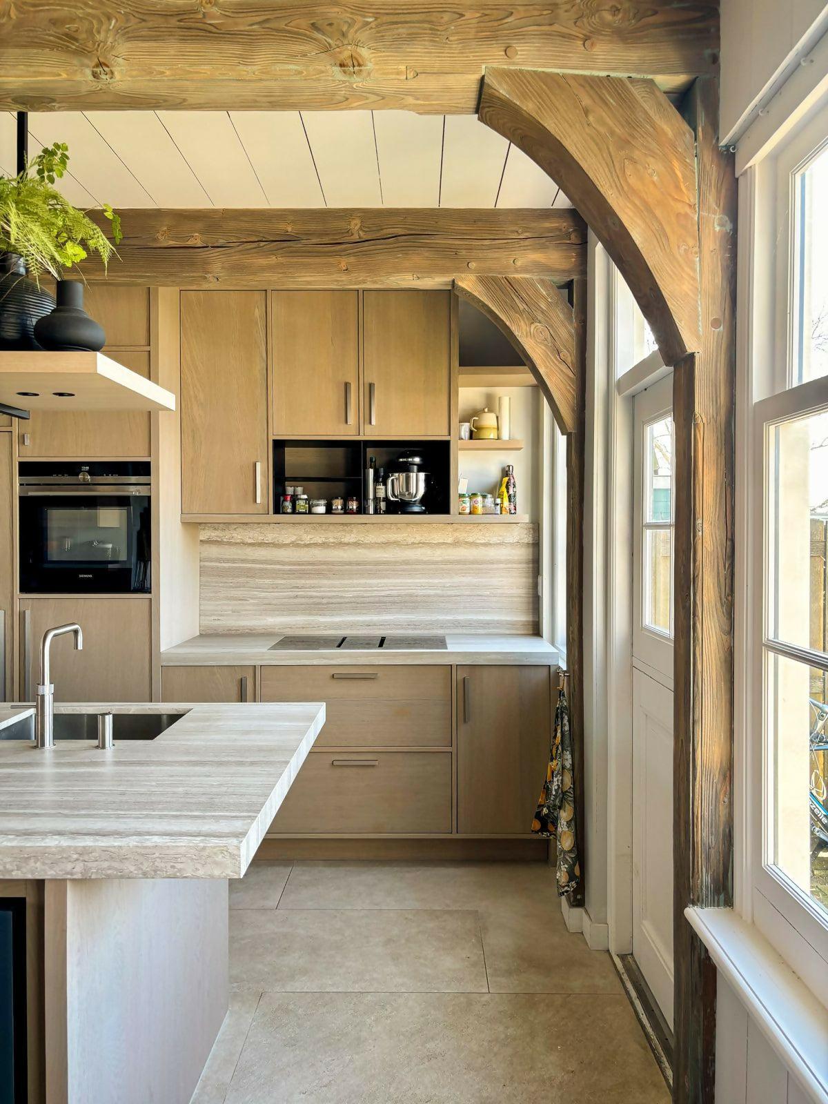 Speelse maatwerk keuken in traditionele Zaanse woning-Studio A-eikenfineer,grey oak,hout,keuken,keuken ontwerp,maatwerk keuken,marmer werkblad,moderne keuken,rvs details,speels design,stalen elementen,traditionele woning,travertin look,warme materialen,zwarte accenten-Ruim keukenontwerp in Zaanse woning Oostknollendam | Studio Å-OBLY