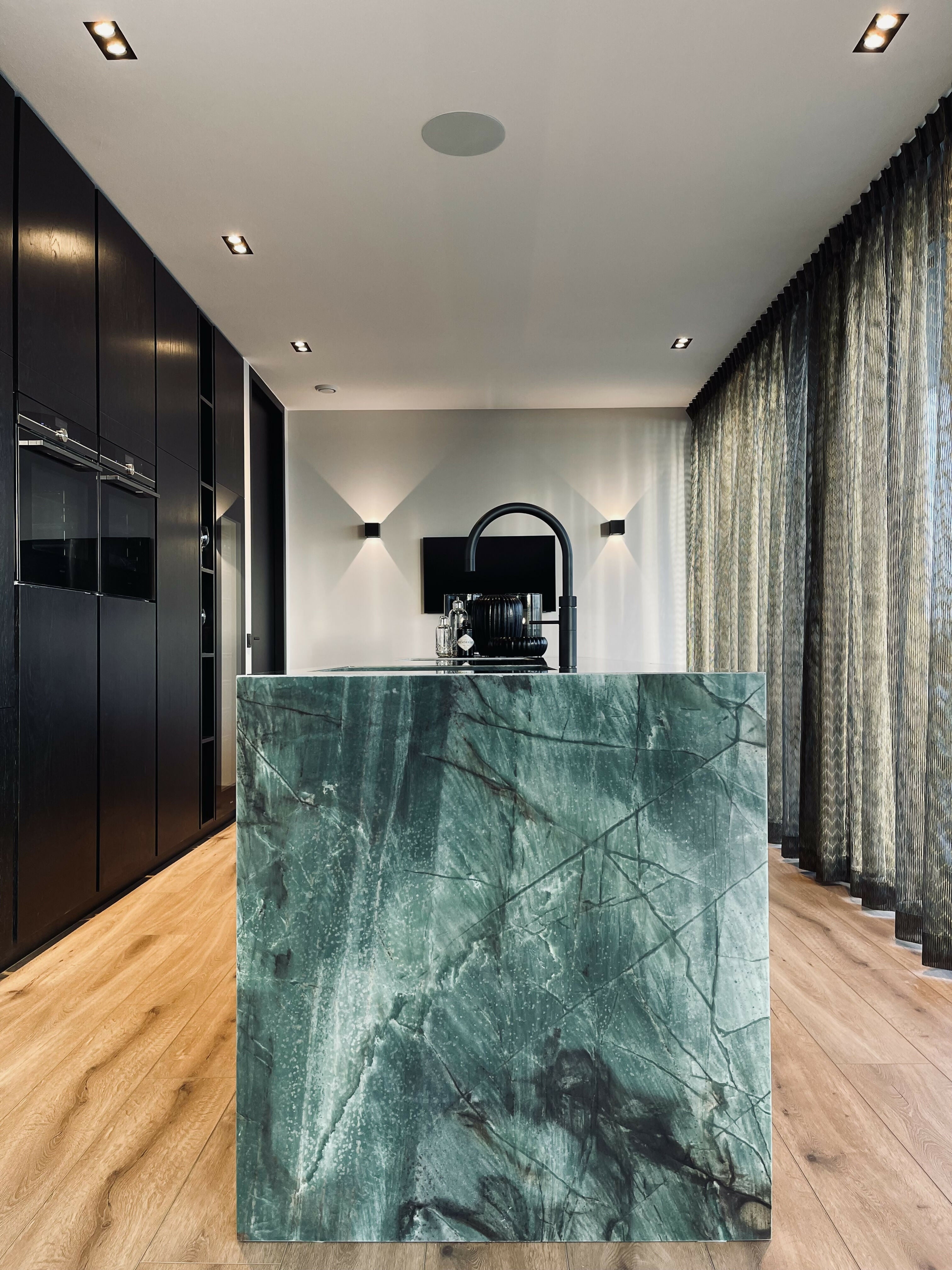 Totaalontwerp met statement keuken en maatwerkdetails-L4 Elvire-gordijnen,hoogwaardige materialen,lichtinval,minimalistisch design,moderne woning,open keuken,sfeervolle verlichting,strak interieur,wandarmaturen,warme uitstraling,zwarte kastenwand-Totaalinterieur met statement keuken in natuursteen | STUDIO L4-OBLY