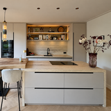 Lichte maatwerk keuken met travertinlook kookeiland en open wandplanken