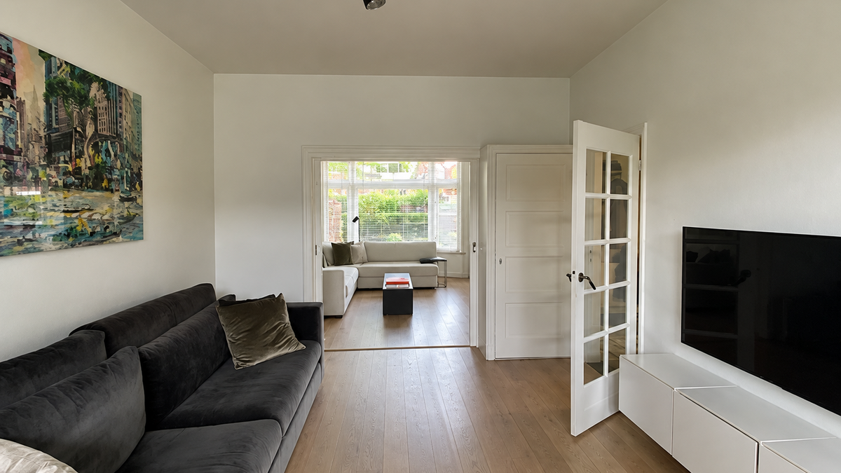 Before: oorspronkelijke woonkamer van een jaren ’30 woning in Breda, met een kamer-en-suite-indeling, houten vloer en glazen binnendeur naar de zitkamer met erker.