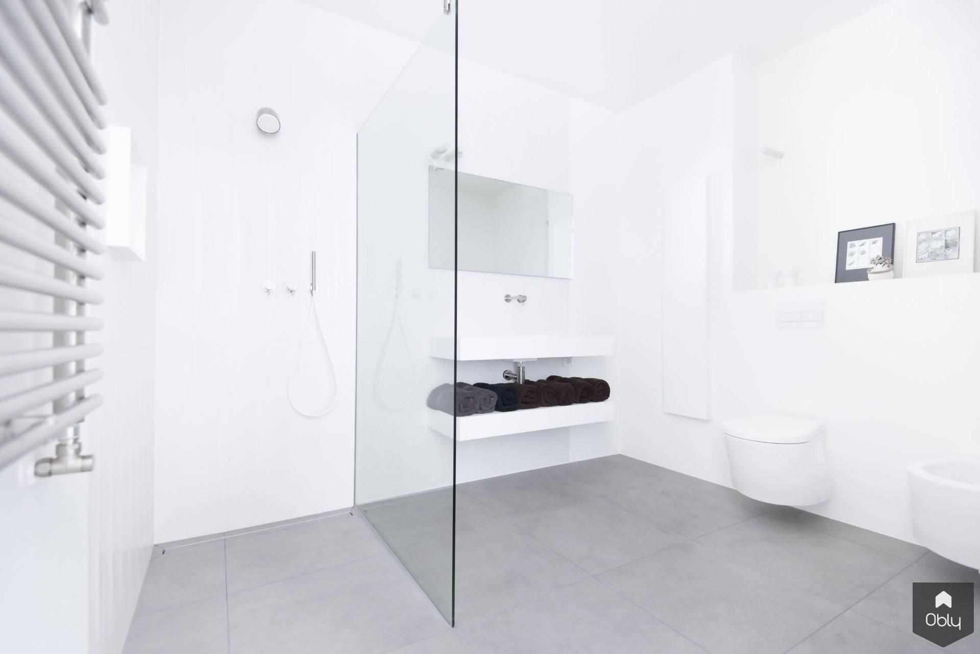 Minimalistische witte badkamer-Fors design badkamers-alle,Badkamer,badkamer met inloopdouche glaswand,badkamer met zwevend meubel wit,kleine witte badkamer ideeën,lichte badkamer met daglicht,minimalistisch interieur badkamer,minimalistische witte badkamer,moderne witte badkamer inspiratie,strakke badkamer wit design,witte badkamer met betonlook vloer-Minimalistische witte badkamer | OBLY.com-OBLY
