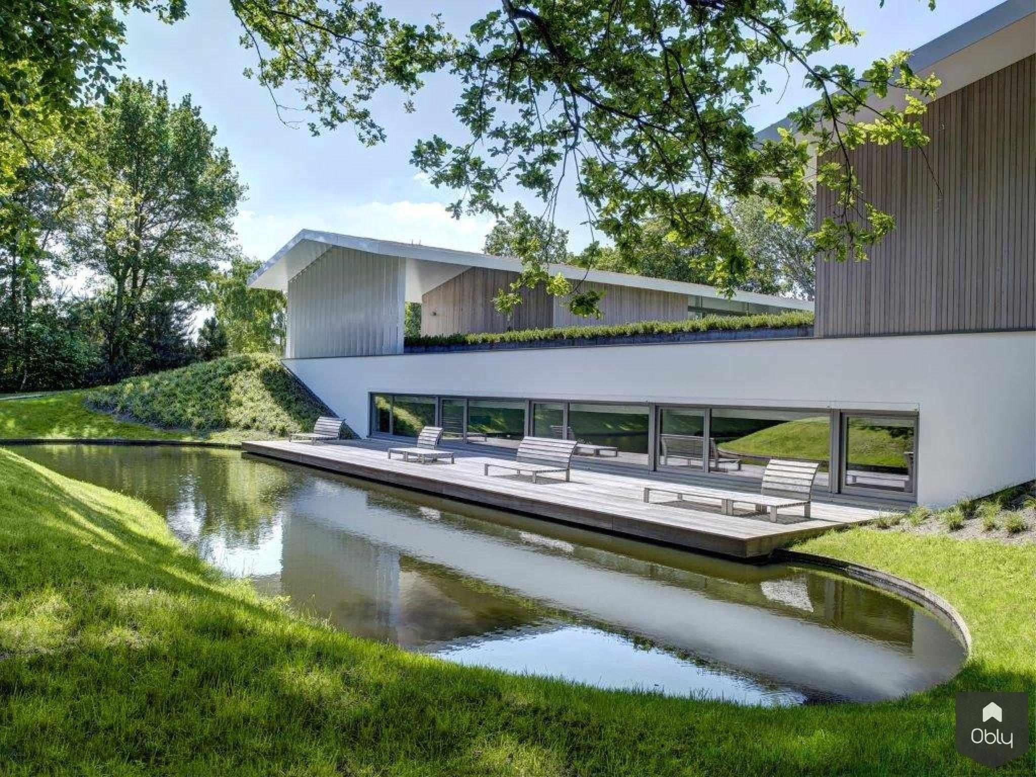 Waterdoorlatende tuin bij villa-Kamsteeg Tuinen-alle,duurzamebuitenruimte,klimaatadaptievetuin,modernevilla,natuurlijkevijver,Tuinen,villatuin,wadi,waterdoorlatendetuin,Woonkamer,zwembadtuin-OBLY
